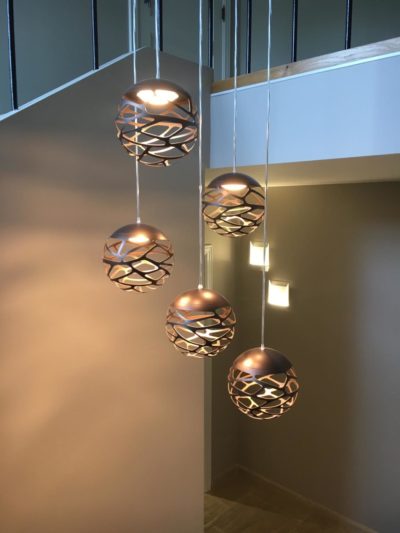 Un lustre Studio Italia avec cinq boules en couleur bronze pour une lumière chaude dans toute la cage d’escalier.