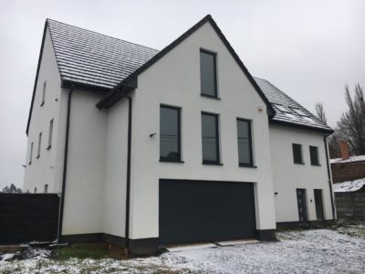 Façade blanche et éclairage extérieur d’une maison passive.