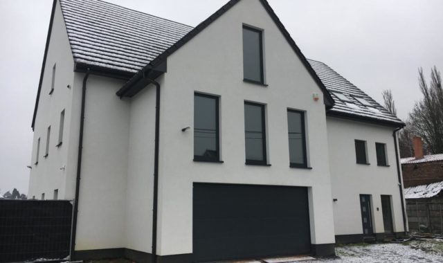 Façade blanche et éclairage extérieur d’une maison passive.