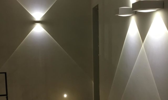 éclairage intérieur d’un couloir avec appliques murales et balises intégrées.